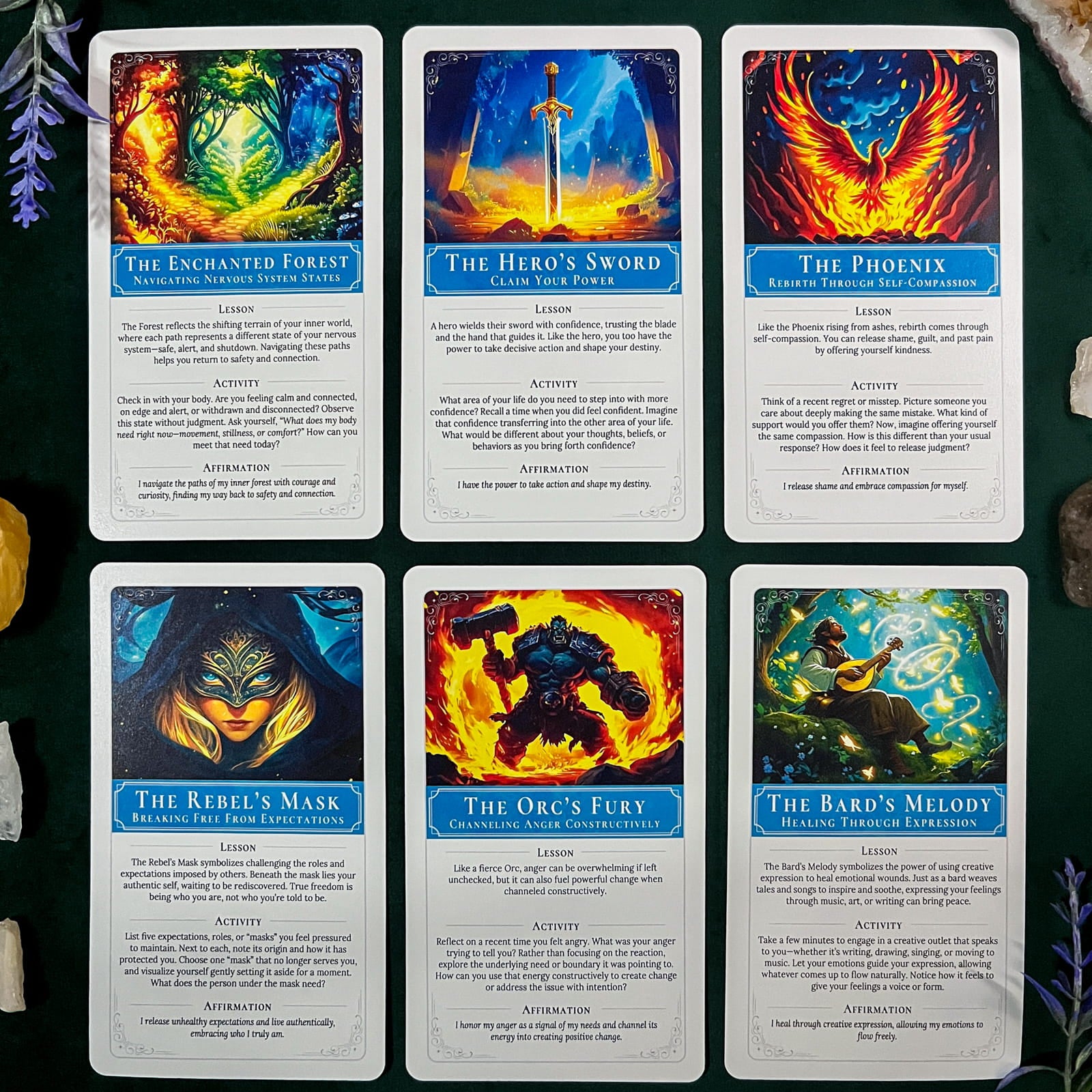 Six fantasy-themed self-discovery cards arranged in a 2x3 grid on a dark green textured surface with small decorative props at the corners. The cards feature colorful illustrated artwork and blue title banners reading titles such as The Enchanted Forest, The Hero's Sword, The Phoenix, The Rebel's Mask, The Orc's Fury, and The Bard's Melody.
